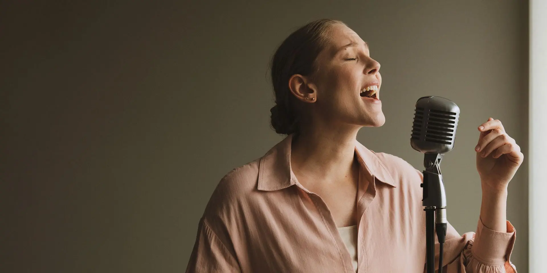 A woman singing into a studio microphone